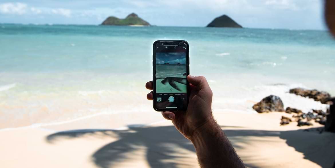 a phone in a paradisiac beach with eSim Data Plan for Travel