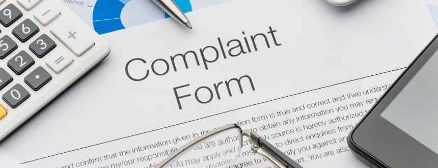A complaint form surrounded by a pen, glasses, calculator and pen. Although you may think complaining needs to be a lengthy & stressful process, it's actually quite simple!